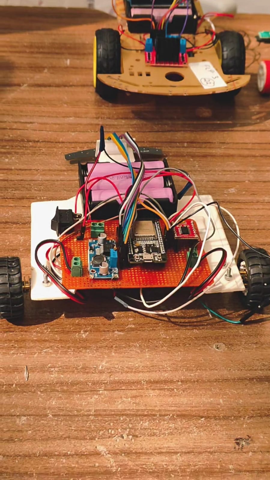 Handmade robot chassis with exposed wiring and lithium batteries on a wooden bench