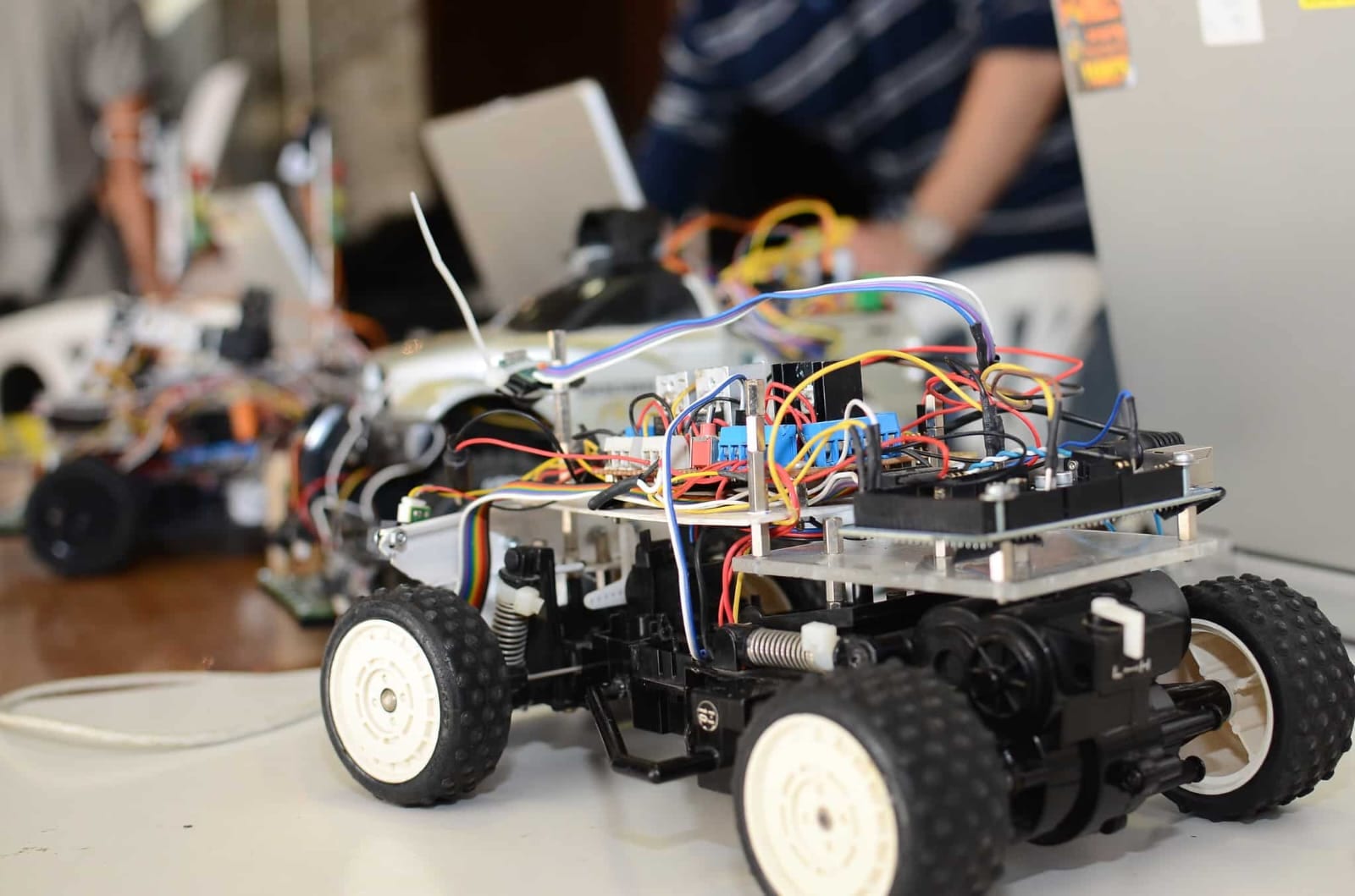 Close-up of a wheeled robot with dense multi-colored wiring on a workshop table