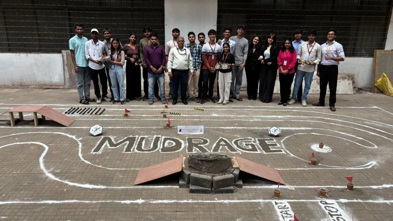 Team posing behind the MUDRAGE outdoor robotics competition track with ramps and obstacles