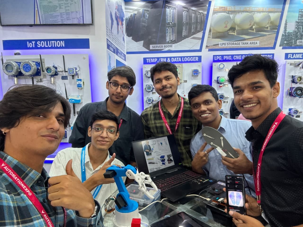 Team at Automation Expo with a robotic arm prototype, laptop, and sensor demo