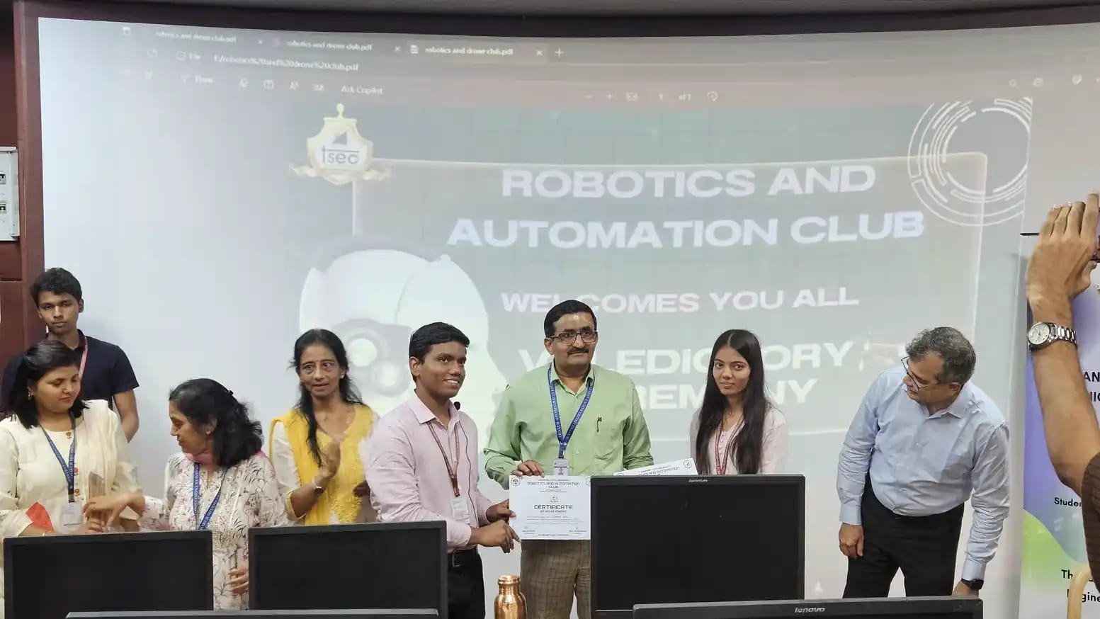 Certificate presentation under a Robotics and Automation Club welcome screen